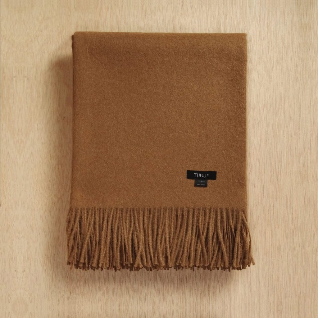 alpaca blanket in camel color by Tukuy on top of a wooden background