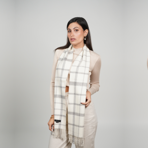 Woman wearing a white and gray check alpaca scarf with a timeless windowpane pattern, showcasing its elegant drape, soft alpaca wool texture, and versatile neutral color palette.