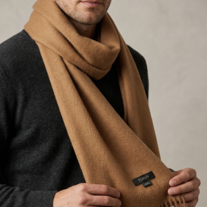 Men wearing a camel alpaca wool scarf in a natural camel color, paired with a charcoal sweater for a timeless winter look.