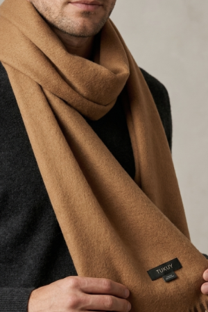 Men wearing a camel alpaca wool scarf in a natural camel color, paired with a charcoal sweater for a timeless winter look.