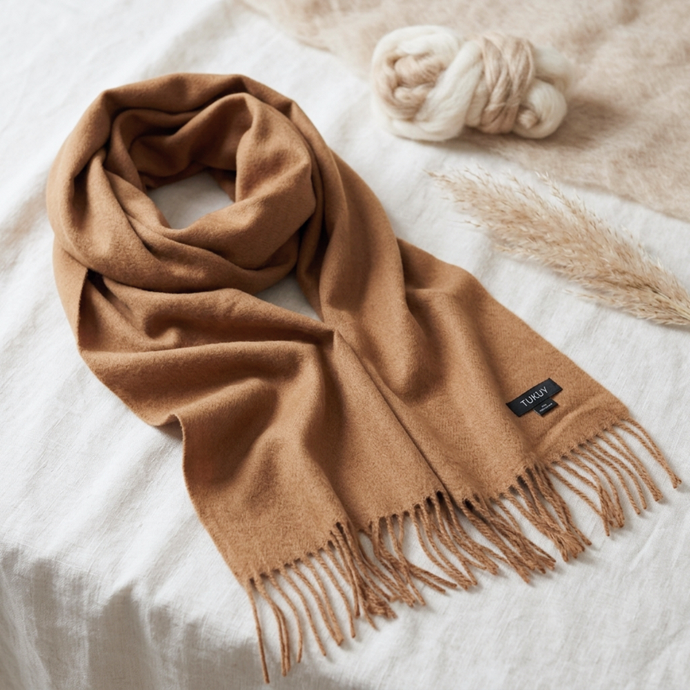 Camel alpaca wool scarf in a warm natural camel tone with fringed edges, displayed on a neutral linen background.