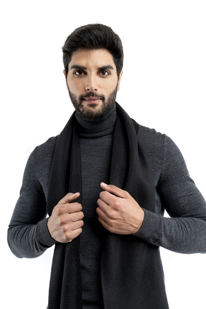 Man wearing a black baby alpaca scarf from Tukuy, styled over a dark turtleneck and brown trousers