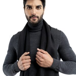 Man wearing a black baby alpaca scarf from Tukuy, styled over a dark turtleneck and brown trousers