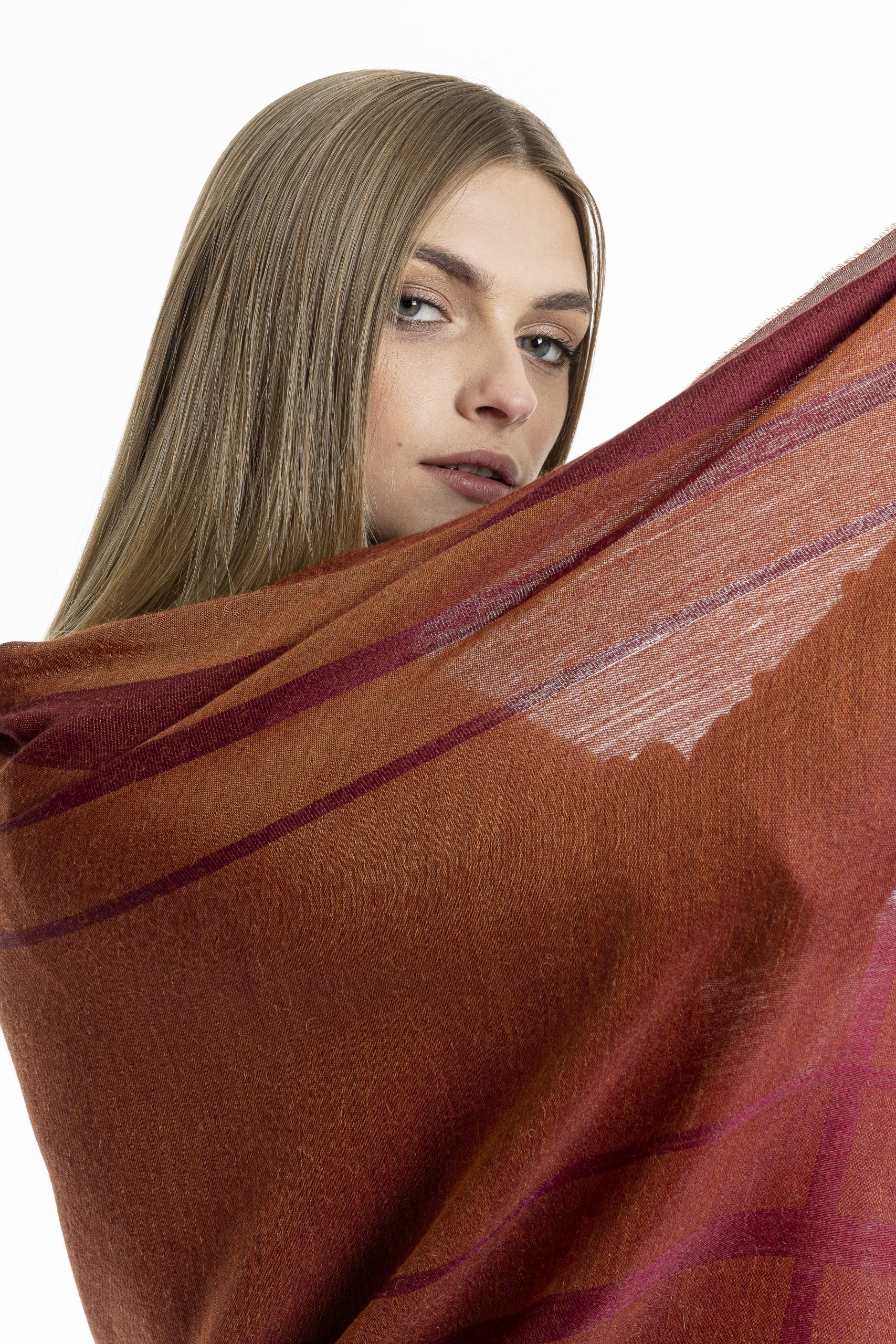 Woman wearing a lightweight burgundy striped shawl made from baby alpaca and silk, styled over a black outfit against a white background.
