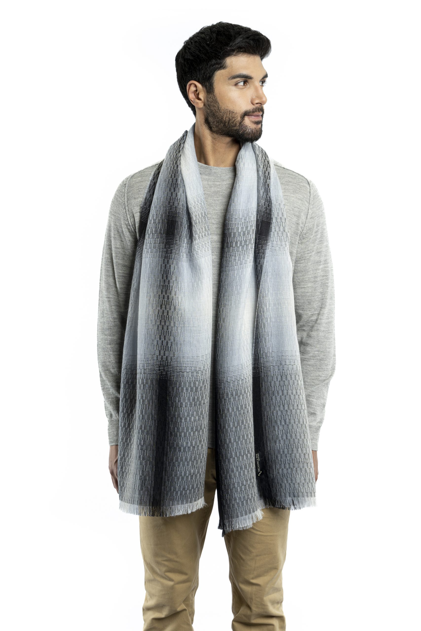 Man wearing a dark grey baby alpaca wool and silk shawl with light grey stripes from Tukuy, styled over a light grey sweater