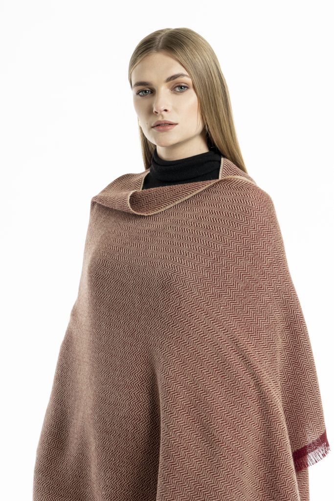 woman wearing a red herringbone-patterned baby alpaca wool scarf from Tukuy with burgundy fringed edges, styled over a black outfit