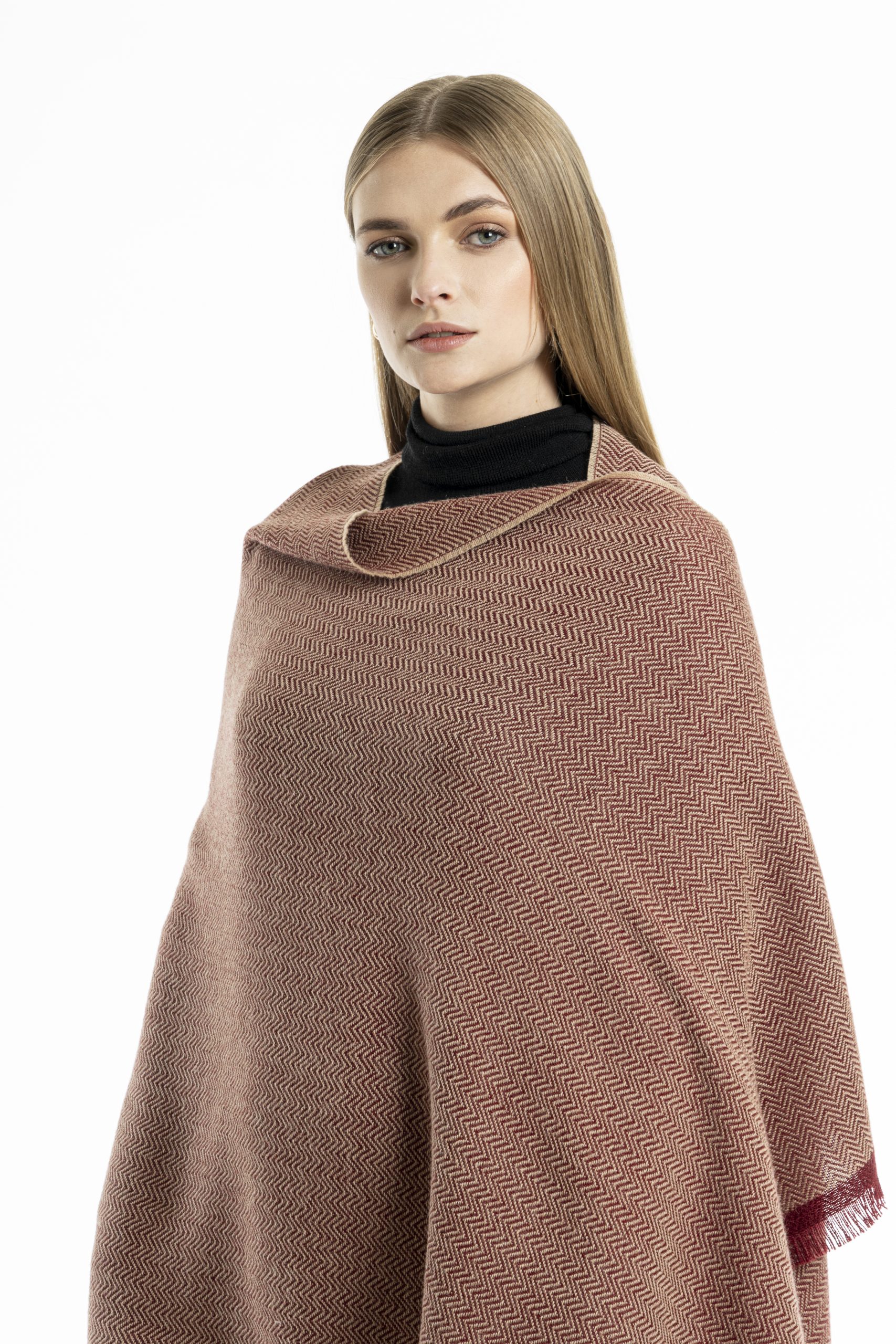 woman wearing a red herringbone-patterned baby alpaca wool scarf from Tukuy with burgundy fringed edges, styled over a black outfit
