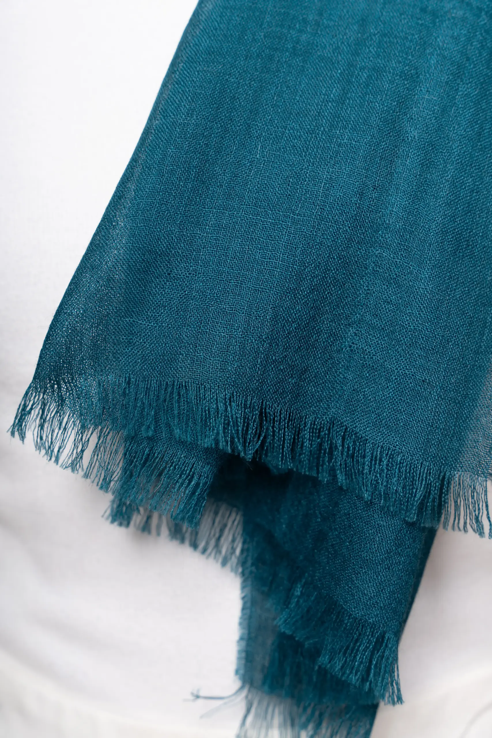 Woman wearing a gradient blue alpaca shawl from Tukuy, styled over a white outfit and posed against a soft beige background.