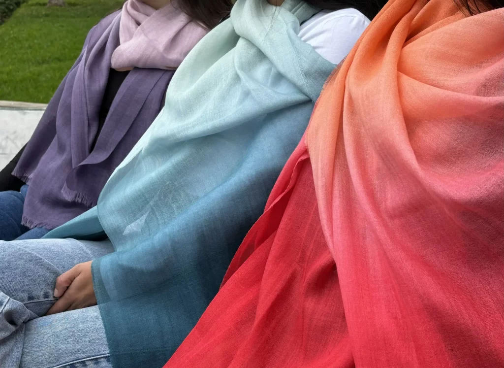 Three people wearing alpaca wool shawls with different colors