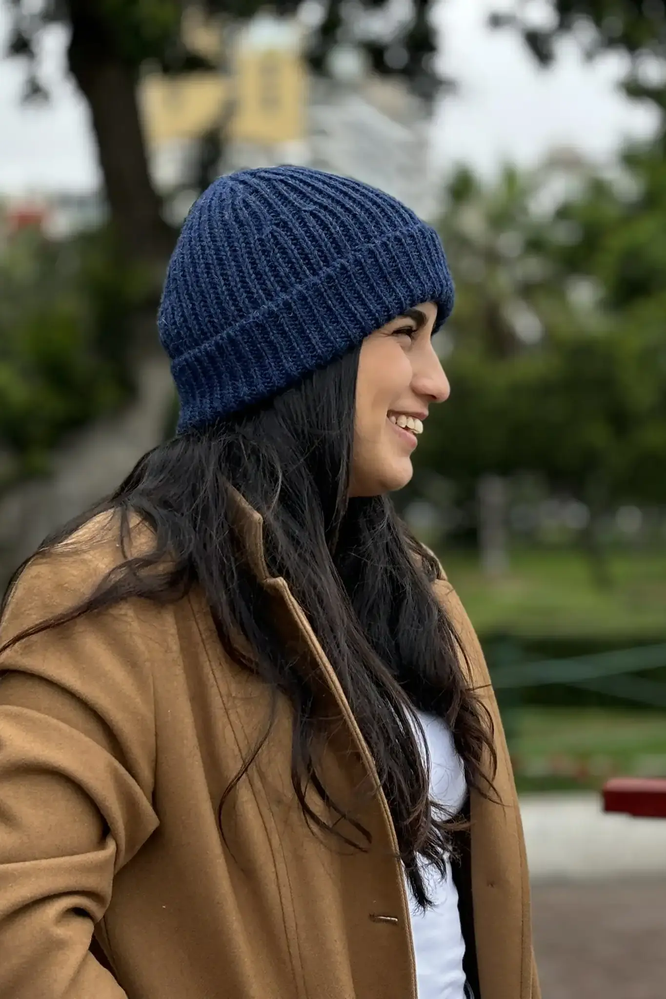 Woman wearing a blue ribbed baby alpaca wool beanie from Tukuy, shown in profile against a natural background.