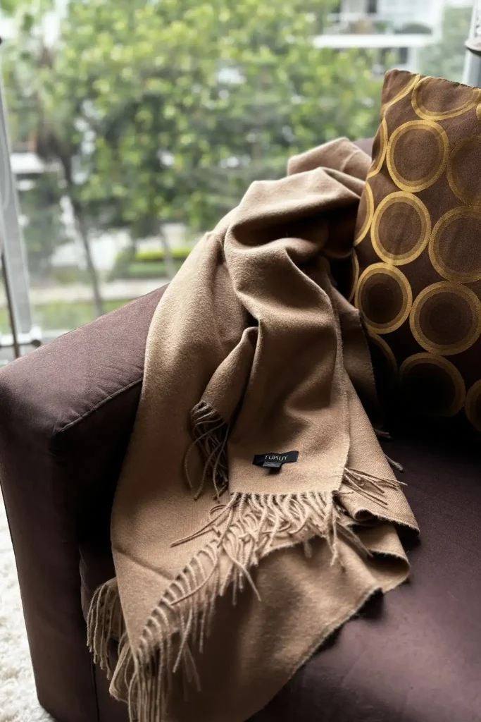 manta de llana d'alpaca de camell estesa sobre un sofà marró