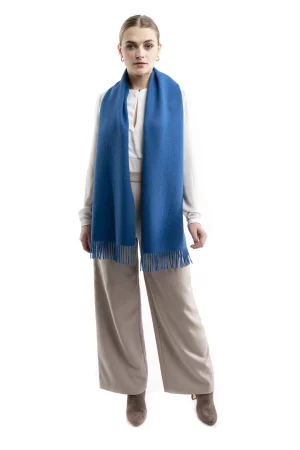 Woman wearing a blue alpaca scarf from Tukuy with fringed edges, styled over a neutral outfit