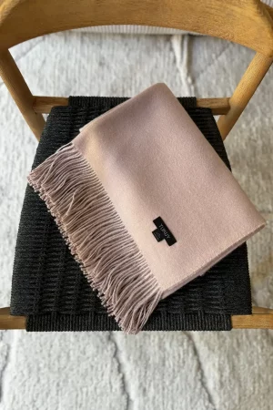 light pink alpaca blanket from Tukuy draped over a wooden chair in a modern living room