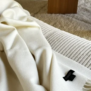 manta blanca de lana de baby alpaca de Tukuy sobre el sofá de un acogedor salón