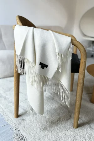 white baby alpaca wool blanket from Tukuy draped over a sofa in a cozy living room