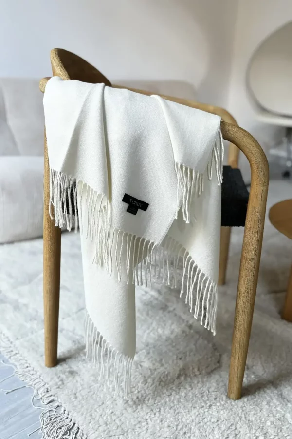 white baby alpaca wool blanket from Tukuy draped over a sofa in a cozy living room