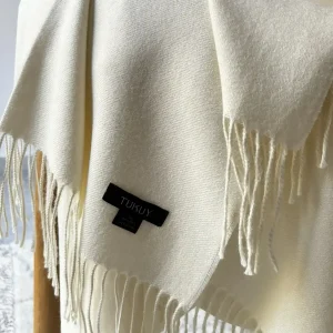 Manta blanca de lana de baby alpaca de Tukuy sobre el sofá de un acogedor salón