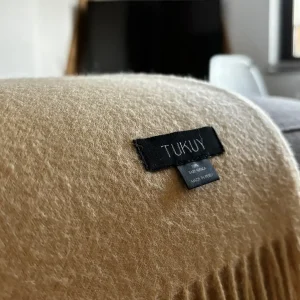 Yellow baby alpaca wool blanket from Tukuy draped over a sofa in a cozy living room