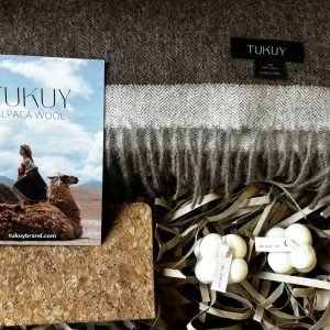 Gift box featuring a brown and beige baby alpaca wool blanket from Tukuy, paired with artisanal candles, a cork notebook, and a brand booklet. Perfect gift for her.