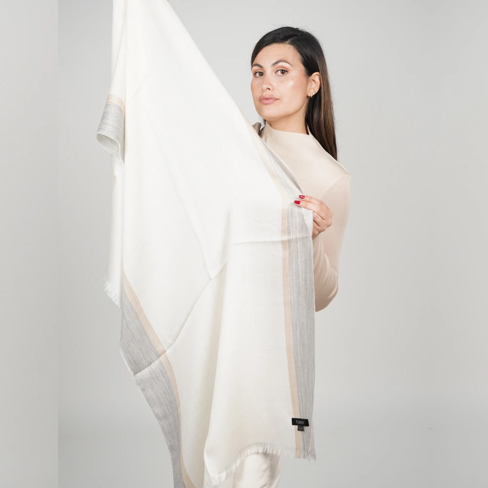 Woman holding a white and gray alpaca shawl showing the design of the product