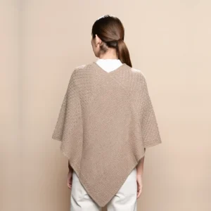 mujer con poncho de baby alpaca beige sobre fondo neutro, mostrando la parte trasera del poncho