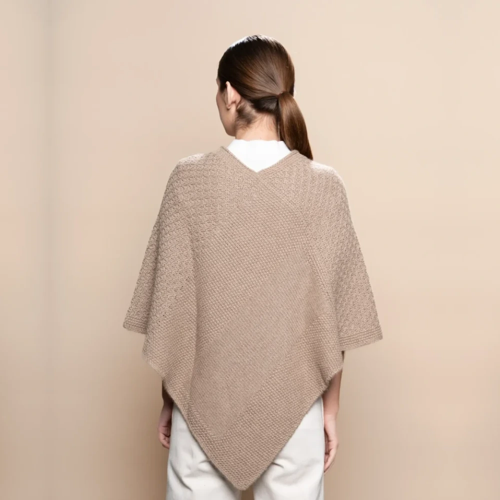 mujer con poncho de baby alpaca beige sobre fondo neutro, mostrando la parte trasera del poncho