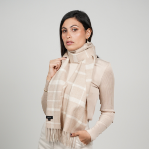 Woman wearing a beige check alpaca scarf featuring a timeless windowpane pattern in soft beige and cream tones, showcasing its elegant drape and versatile neutral styling.