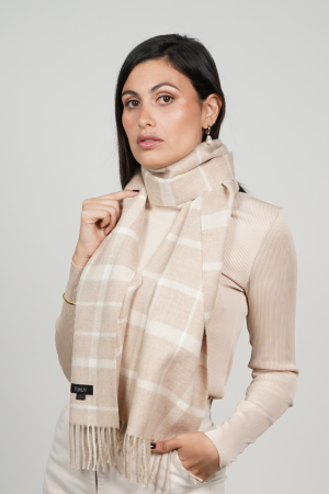 Woman wearing a beige check alpaca scarf featuring a timeless windowpane pattern in soft beige and cream tones, showcasing its elegant drape and versatile neutral styling.