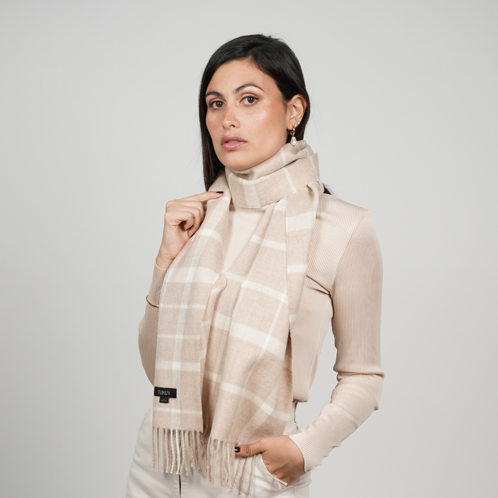 Woman wearing a beige check alpaca scarf featuring a timeless windowpane pattern in soft beige and cream tones, showcasing its elegant drape and versatile neutral styling.