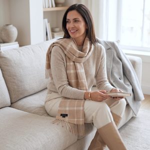 Woman wearing a beige check alpaca scarf with a taupe knit sweater and cream trousers, highlighting the scarf's soft neutral palette and timeless checked design for an elegant everyday look.