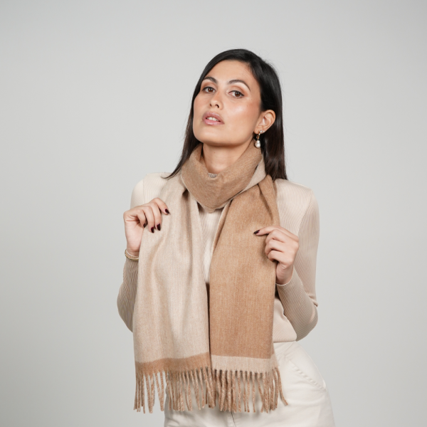Woman wearing a reversible camel and beige alpaca scarf, showcasing the elegant contrast of two natural tones, luxurious softness, and timeless neutral styling.