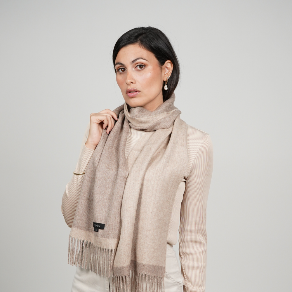 Woman wearing a reversible alpaca wool scarf in natural beige and taupe tones, showcasing its soft texture, elegant drape, and timeless neutral styling.