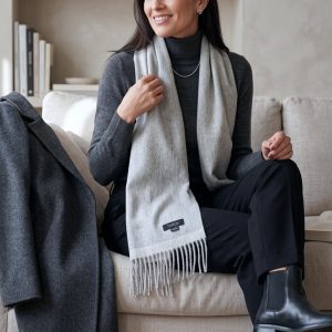 Woman styling a reversible gray alpaca scarf with a charcoal turtleneck and dark trousers, showcasing how soft gray tones pair effortlessly with deep neutrals for an elegant winter outfit.