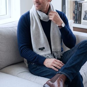 Man wearing a reversible gray alpaca scarf with a navy sweater and denim, highlighting the versatility of natural gray alpaca wool in a refined smart-casual look.