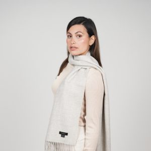 Woman styling the Ayllu light gray alpaca scarf, a timeless accessory crafted from natural baby alpaca wool.