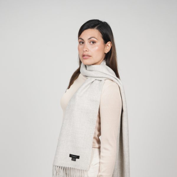 Woman styling the Ayllu light gray alpaca scarf, a timeless accessory crafted from natural baby alpaca wool.