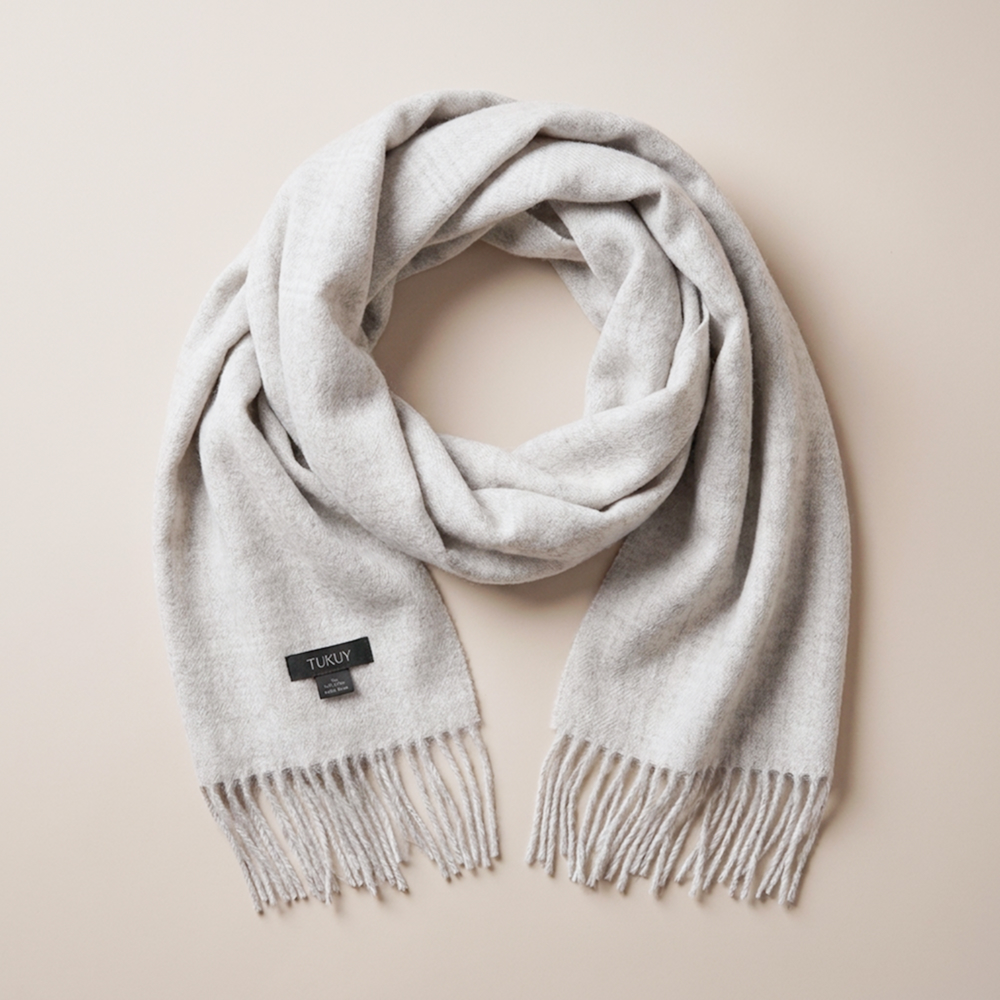Folded light gray alpaca scarf made from 100% baby alpaca wool with hand-finished fringes.
