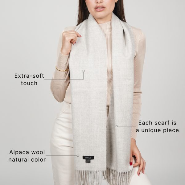 Woman wearing the Ayllu undyed light gray baby alpaca scarf made in Peru, showcasing its natural color and soft texture.
