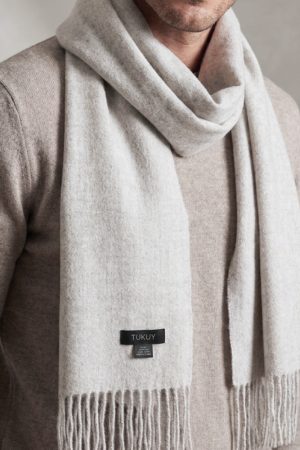 Man wearing the Ayllu light gray alpaca scarf crafted in Peru from 100% baby alpaca wool.