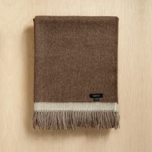 Baby alpaca blanket in brown folded on a neutral background with elegant fringe