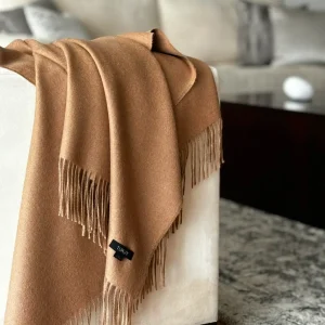 Camel baby alpaca blanket draped over a sofa with fringed edges โ soft, warm Peruvian alpaca wool throw for home dรฉcor
