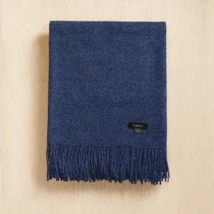 Baby alpaca blanket in deep blue folded on a neutral background with elegant fringe