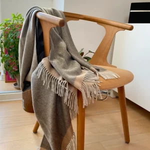 Baby alpaca blanket in grey styled over a wooden chair in a modern home