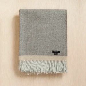 Baby alpaca blanket in grey folded on a neutral background with fringe details