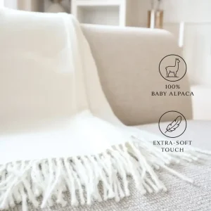 Baby alpaca blanket in white draped over a sofa highlighting its soft texture