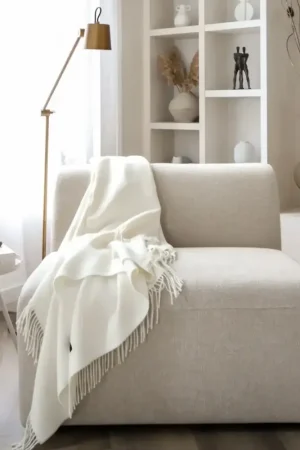 Baby alpaca blanket in white styled on a sofa in a bright modern living room