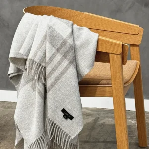 Baby alpaca blanket in light grey check draped over a wooden chair