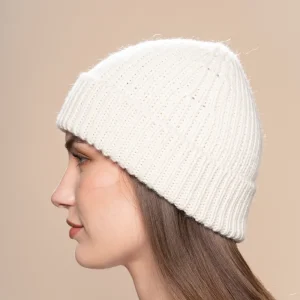 women in profile wearing a white knitted alpaca beanie in a neutral background