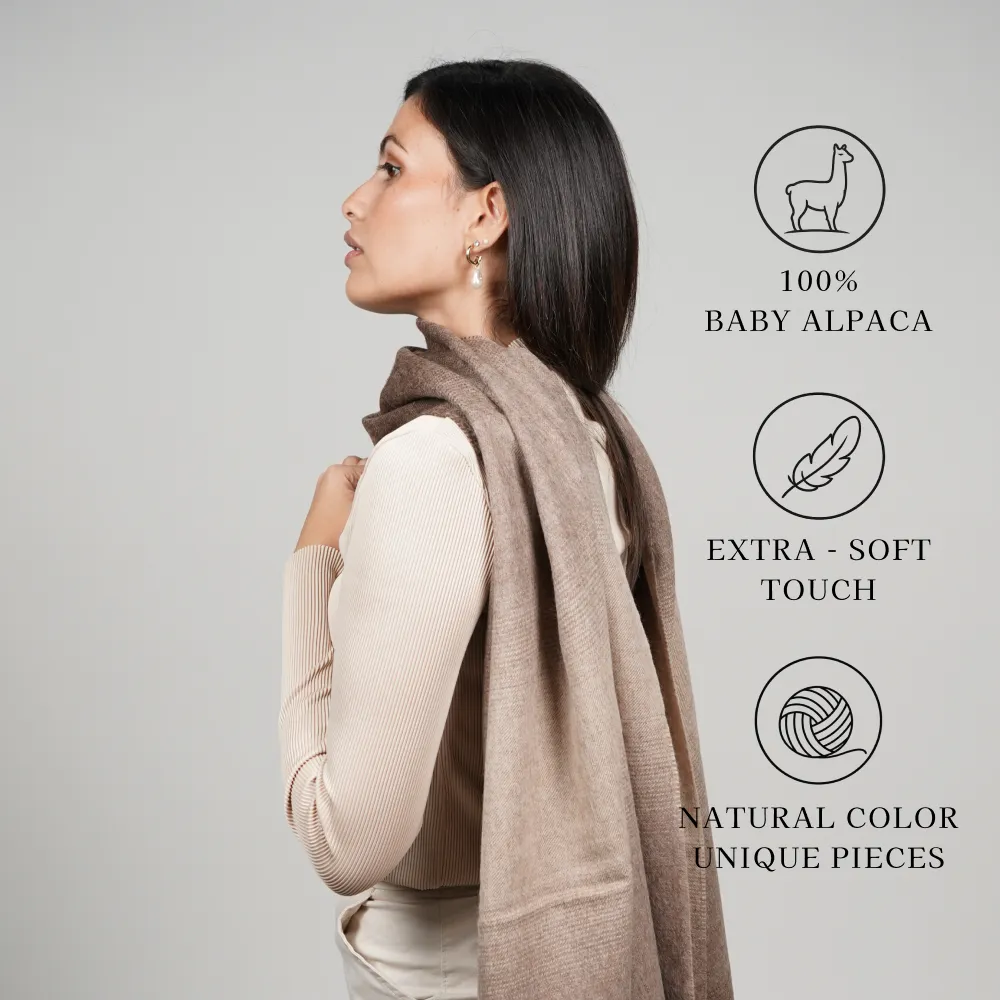 Model wearing a brown alpaca shawl graphic states 100% baby alpaca, extra-soft touch, and unique pieces