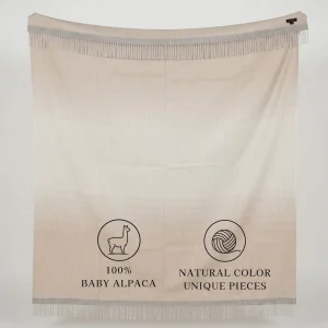 Cream-colored fringed alpaca blanket labeled “100% Baby Alpaca” and “Natural Color, Unique Pieces”